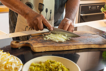 Man Preparing Fresh Vegetables on Wooden Cutting Board in Kitchen