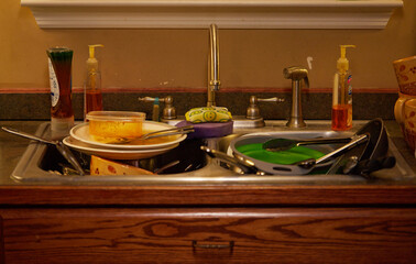 Dirty dishes and pots and pans sitting in the sink waiting to be washed!