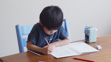 ひらがなのを書く練習をする5歳の男の子