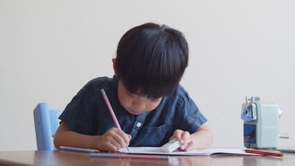 ひらがなのを書く練習をする5歳の男の子