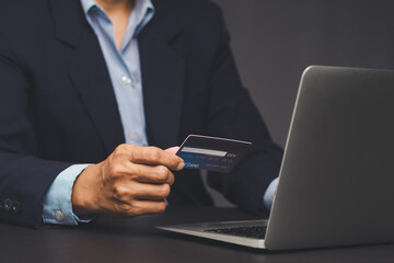 Businessman holding credit card using laptop for online payment.