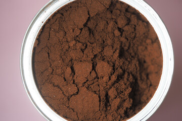Coffee grounds in a container on a pink background