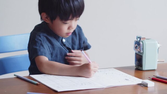 ひらがなのを書く練習をする5歳の男の子