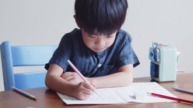 ひらがなのを書く練習をする5歳の男の子