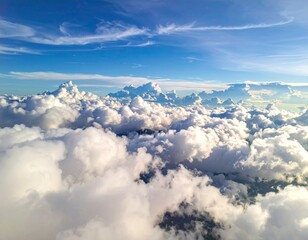 Cloudscape from above.  Vast expanse of puffy white clouds, scattered across a brilliant blue sky.  Sunlight illuminates the scene