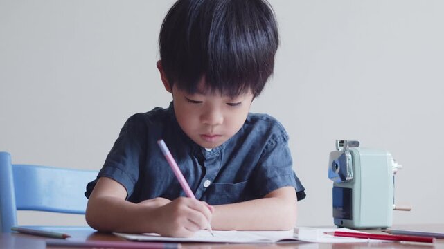 ひらがなのを書く練習をする5歳の男の子