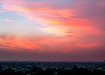 Lahore skyline at sunset with ominous red sky and dramatic motion, capturing the city's silhouette against a vibrant orange and pink hues backdrop,