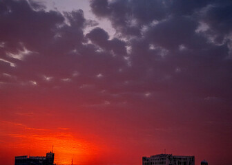 Lahore skyline at sunset with ominous red sky and dramatic motion, capturing the city's silhouette against a vibrant orange and pink hues backdrop,