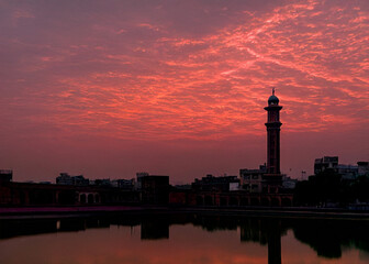 Lahore skyline at sunset with ominous red sky and dramatic motion, capturing the city's silhouette against a vibrant orange and pink hues backdrop,