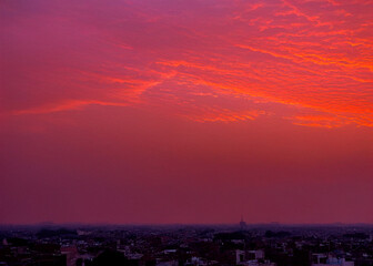 Lahore skyline at sunset with ominous red sky and dramatic motion, capturing the city's silhouette against a vibrant orange and pink hues backdrop,