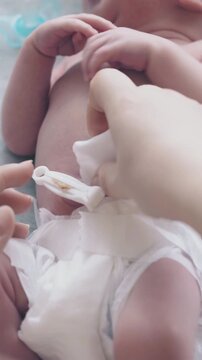 careful mother hands practice newborn baby umbilical cord care on lying infant boy extreme close view