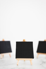 black canvases on miniature easels on white marble, mockup with copy space, shallow dof