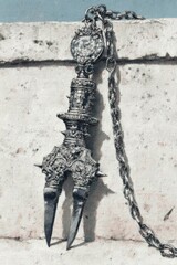 Ornate, forked metal weapon with chain