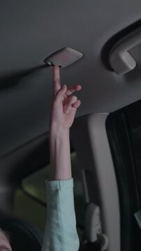 A close view of a child turning off the light in a car, the background shows a dimly lit car interior with blurred lights outside