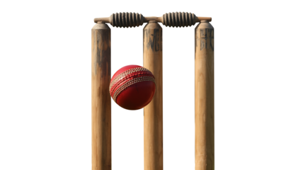 A red cricket ball flying through wooden stumps