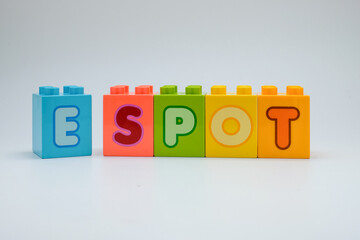 Colorful plastic toy blocks spelling the word E SPOT with alphabet letters arranged in a row on white background. Concept of education, learning, childhood creativity, and playful design