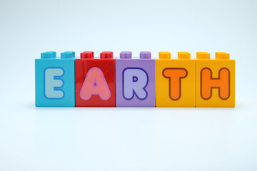Colorful toy blocks with letters spelling EARTH on a clean white background. Perfect for education, environment, children learning, or earth day. Suitable for posters, web, or ads