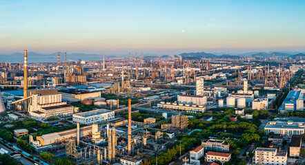Naklejka premium Panoramic view of a large oil refinery and chemical plant in a massive coastal industrial zone at sunset