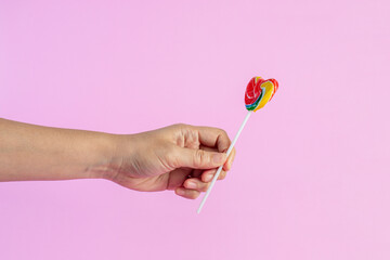 Sweets, two lollipops in hand, on pink background