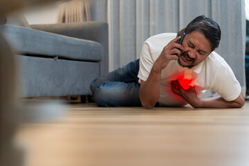 Man suffering chest pain heart attack emergency while calling for help lying on floor at home in pain