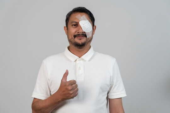 Middle aged man with eye patch after surgery showing thumbs up recovery concept healthcare medical treatment - Powered by Adobe
