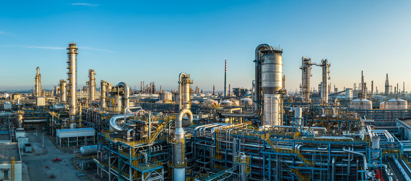 A large oil refinery and petrochemical plant with complex industrial equipment at sunset