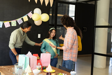 In office, diverse group celebrating baby shower, congratulating expectant mother