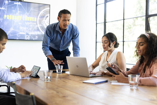 Business team collaborating on laptops and tablets during product launch meeting - Powered by Adobe