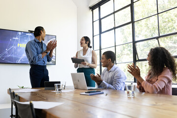 Business team applauding colleague during presentation in modern conference room