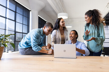 Collaborating in modern office, diverse business team sharing ideas around laptop