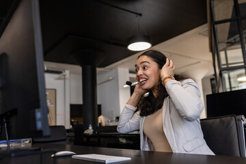 Businesswoman in office smiling while using headset for video conference call