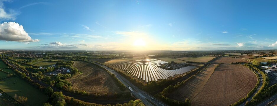 Wide angle aerial drone view of Solar power plant, photovoltaic panels and rural landscape, energy generation electricity at sunset summer Leicestershire England UK