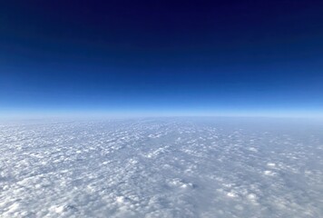 A stunning view of a cloudscape meeting the dark-blue sky, seen from above the clouds, creating a calming and expansive aerial panorama
