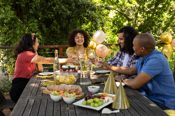 Toasting with wine glasses, friends celebrating and sharing festive meal outdoors