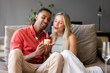 Celebrating with cupcake, couple smiling on couch, sharing special moment together