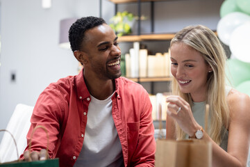 Happy couple exchanging gifts at home, enjoying joyful celebration together