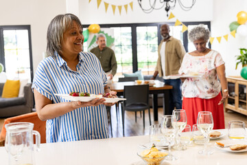 Smiling woman serving food at family gathering, celebrating indoors with loved ones