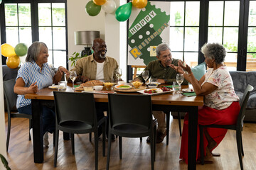Smiling friends celebrating retirement with food and drinks at home