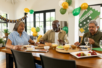 Celebrating retirement, diverse group sharing meal at home, smiling and talking