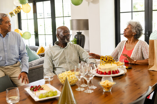 Family celebrating 60th birthday with cake and decorations at home, sharing stories