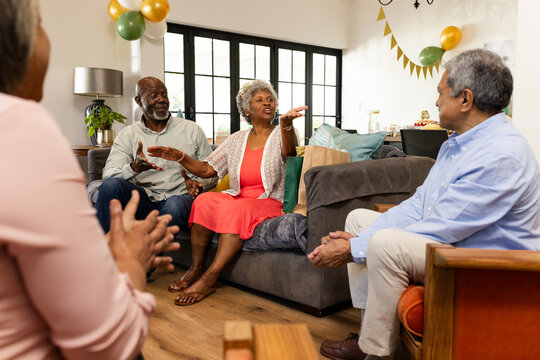 Elderly friends laughing and sharing stories in cozy living room celebration