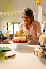 Smiling woman arranging cake decorations for 60th birthday celebration at home