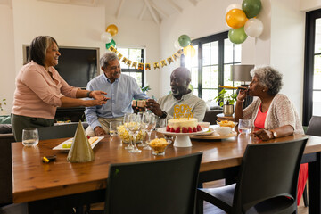 Family celebrating birthday at home, sharing cake and drinks with joy