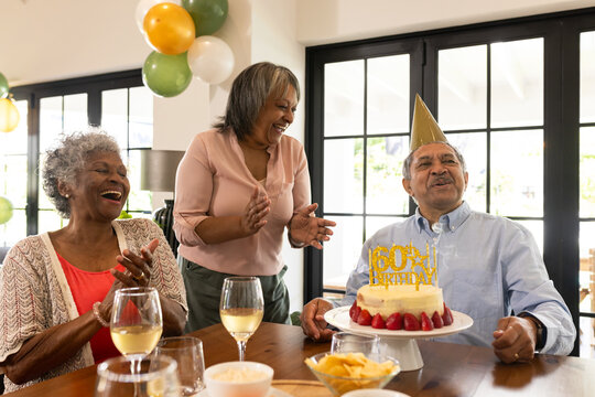 Celebrating birthday, elderly man with cake and friends sharing joyful moment together - Powered by Adobe