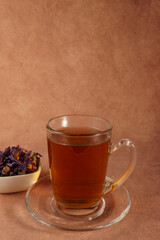 Glass cup of steaming mallow tea with dried mallow flowers in a small white bowl, promoting relaxation and wellness