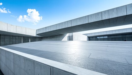Obraz premium A wide, sun-drenched concrete plaza surrounded by clean, geometric concrete structures that create a stark, minimalist landscape under a blue sky.