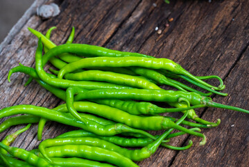 Fresh organic green chili peppers arranged on an old rustic wooden surface. Long, spicy green peppers freshly harvested from the farm.