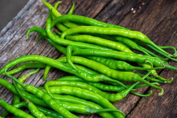 Fresh organic green chili peppers arranged on an old rustic wooden surface. Long, spicy green peppers freshly harvested from the farm.