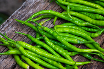 Fresh organic green chili peppers arranged on an old rustic wooden surface. Long, spicy green peppers freshly harvested from the farm.
