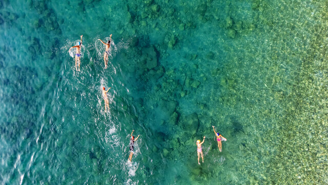 Aerial drone view of people swimming in turquoise sea, group of swimmers training in clear water, open water swimming and triathlon sport